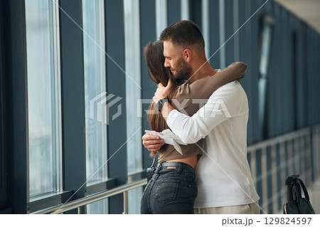 Preparing for long flight, embracing each other. Couple are in the airport hall together 129824597