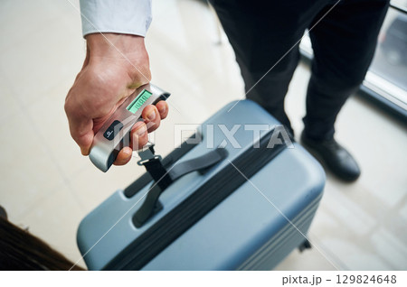 Weight of luggage bag. Close up view of man in formal clothes, conception of airport travel 129824648