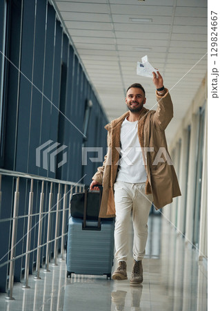 Running, late for flight, with tickets in hand. Young handsome man in the airport Running, late for flight, with tickets in hand. Young handsome man in the airport 129824667
