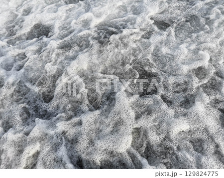 Ocean waves crashing with foam creating a dynamic texture and movement in the water Ocean waves crashing with foam creating a dynamic texture and movement in the water 129824775