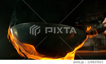 Freeze Motion of Empty Wok Pan with Flames Burning Around. Kitchen Interior on Background. Freeze Motion of Empty Wok Pan with Flames Burning Around. Kitchen Interior on Background. 129825021