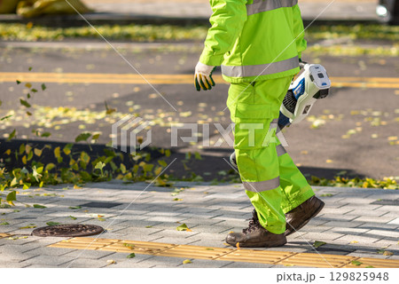 Worker Cleaning Sidewalk with Leaf Blower 129825948