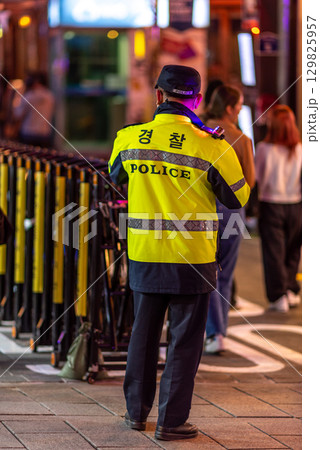 A police officer in a yellow jacket stands on a busy street at night in Seoul, South Korea A police officer in a yellow jacket stands on a busy street at night in Seoul, South Korea 129825957