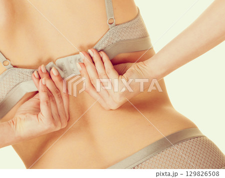 Attractive slim woman taking off grey bra 129826508