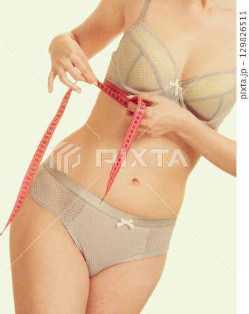 Woman measuring her under breasts. 129826511