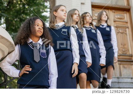Teenage girls in uniform posing seriously on stairs of historic building as editorial group Teenage girls in uniform posing seriously on stairs of historic building as editorial group 129826730