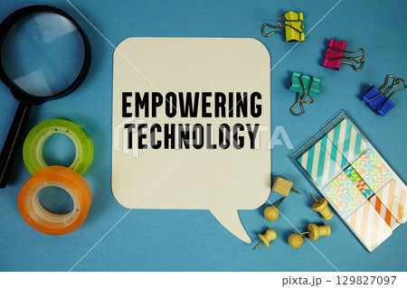 Empowering Technology text with magnifying glass on blue background 129827097