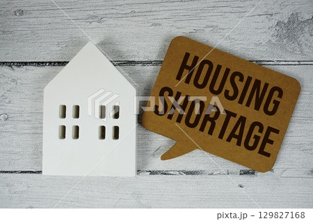Housing Shortage text with house models on wooden background 129827168
