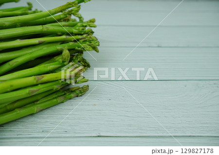 Bunch of fresh green asparagus stems on wooden background 129827178