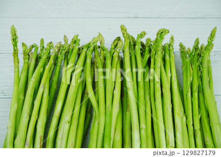 Bunch of fresh green asparagus stems on wooden background 129827179