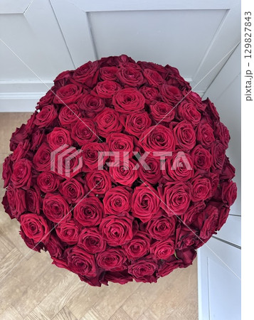 Large bouquet of red roses arranged in round shape. 129827843