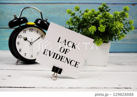 Lack Of Evidence text written on paper card with alarm clock on wooden background Lack Of Evidence text written on paper card with alarm clock on wooden background 129828088