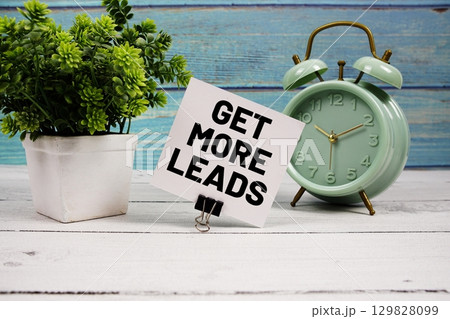 Get More Leads text written on paper card with alarm clock on wooden background 129828099