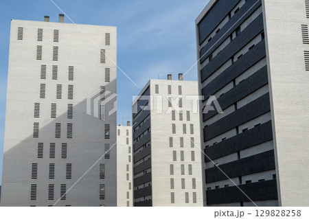 Low angle architectural composition highlighting geometric residential facades, creating visual rhythm with bold color contrasts against vibrant skyline 129828258