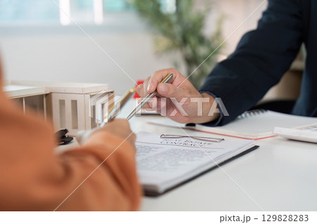 Real Estate Consultation. Client and agent reviewing contract details together. 129828283