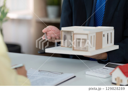 Real estate agent handing over house model to client during consultation Real estate agent handing over house model to client during consultation 129828289