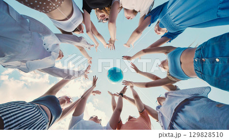 Students reaching for a globe, symbolizing global citizenship, environmental awareness, and international cooperation for a sustainable future 129828510