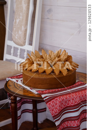 Rustic Ukrainian Honey Cake Decorated with Traditional Pastries, White Tablecloth, Wooden Furniture, Warm Lighting. Rustic Ukrainian Honey Cake Decorated with Traditional Pastries, White Tablecloth, Wooden Furniture, Warm Lighting. 129828533