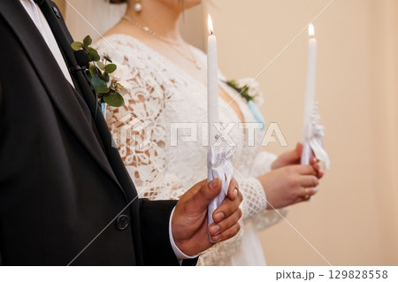 Wedding Ceremony Unity Candle Lighting with Bride in Lace Dress and Groom in Black Suit, Symbolizing Love, Commitment, and Faith. Wedding Ceremony Unity Candle Lighting with Bride in Lace Dress and Groom in Black Suit, Symbolizing Love, Commitment, and Faith. 129828558