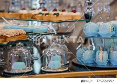 Luxurious Blue Pastel Dessert Buffet Display Featuring Macarons, Cakes, and Pastries in Elegant Silver Stands, Festive Celebration, Soft Focus 129828597