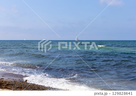 Blue sea with waves, clear weather, and a yacht far away. Blue sea with waves, clear weather, and a yacht far away. 129828641