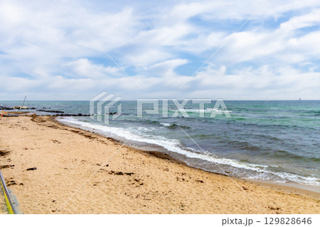 A lengthy beach with golden sand, seaweed lying on the sand 129828646
