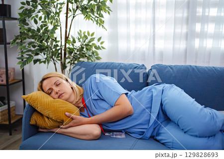 Exhausted Female Doctor Sleeping on Couch After Long Shift at Hospital Exhausted Female Doctor Sleeping on Couch After Long Shift at Hospital 129828693
