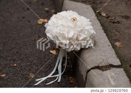 Wedding Rings Resting on a White Hydrangea Flower Beside a Concrete Curb. Romantic Outdoor Ceremony Detail Shot, Neutral Tones Wedding Rings Resting on a White Hydrangea Flower Beside a Concrete Curb. Romantic Outdoor Ceremony Detail Shot, Neutral Tones 129828760
