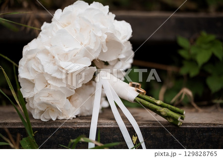 White Hydrangea Bridal Bouquet with Wedding Rings Rustic Outdoor Ceremony, Ivory Flowers, Romantic Engagement, Detailed Close-Up Shot. White Hydrangea Bridal Bouquet with Wedding Rings Rustic Outdoor Ceremony, Ivory Flowers, Romantic Engagement, Detailed Close-Up Shot. 129828765