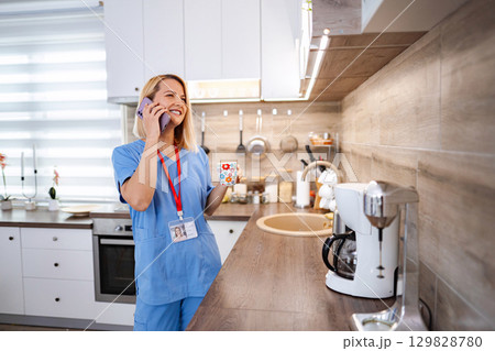 Young female doctor is enjoying her coffee break at home, talking on the phone Young female doctor is enjoying her coffee break at home, talking on the phone 129828780