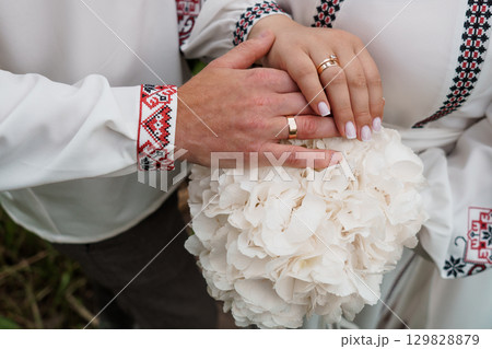 Ukrainian Wedding Hands with Gold Rings and Embroidered Shirts Bouquet, Traditional Culture, White Flowers, Symbolic Love and Celebration Ukrainian Wedding Hands with Gold Rings and Embroidered Shirts Bouquet, Traditional Culture, White Flowers, Symbolic Love and Celebration 129828879