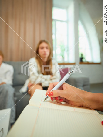 Family therapy session with psychologist taking notes in bright office Family therapy session with psychologist taking notes in bright office 129830356