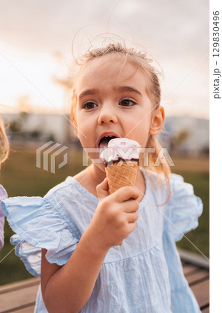 Little girl enjoying ice cream cone outdoors in summer 129830496