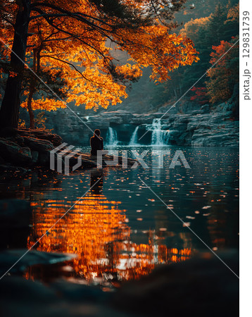 Meditation by a golden waterfall under autumn foliage reflections 129831739