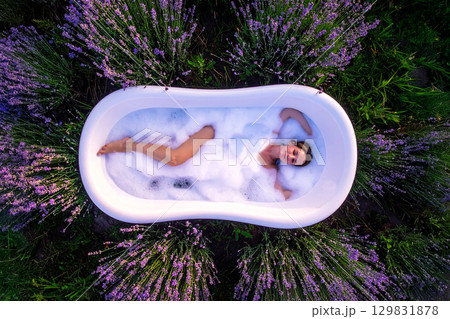 a woman immersed in a bathtub in a flowery meadow 129831878