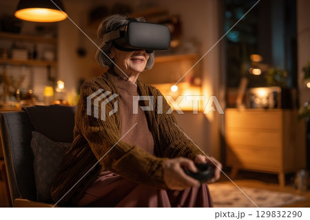 Elderly woman experiencing virtual reality at home with headset and joy on her face Elderly woman experiencing virtual reality at home with headset and joy on her face 129832290