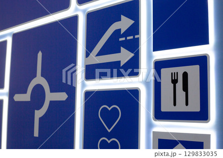 Illuminated road signs on panel, featuring symbols like arrows, roundabout and dining, aimed at teaching children road safety and traffic rules. The design highlights clear, visual instruction Illuminated road signs on panel, featuring symbols like arrows, roundabout and dining, aimed at teaching children road safety and traffic rules. The design highlights clear, visual instruction 129833035