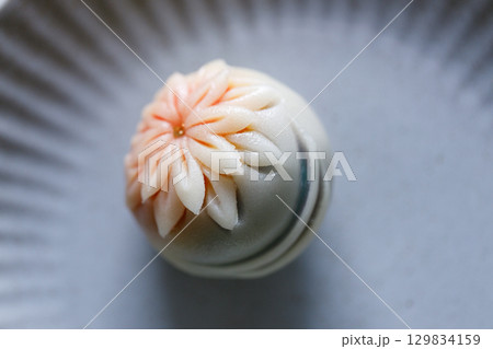A piece of delicious Japanese confectionery on off white ceramic plate on wooden table. 129834159