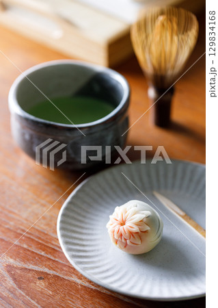 Cup of fresh matcha tea, green tea and Nerikiri, Japanese confectionery, on wooden table. 129834168