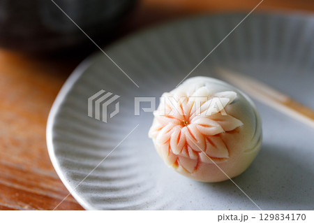 A piece of delicious Japanese confectionery on off white ceramic plate on wooden table. 129834170