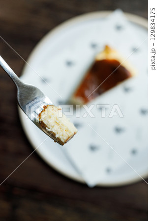 A small piece of cheese cake on a fork. 129834175