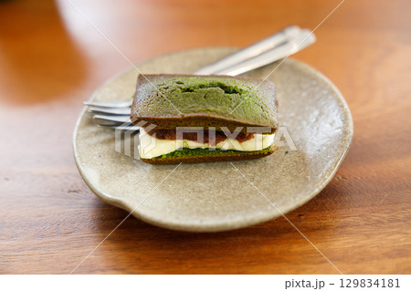 A piece of Cheese and Matcha and red bean paste financier, small French almond cake, on wooden table. A piece of Cheese and Matcha and red bean paste financier, small French almond cake, on wooden table. 129834181