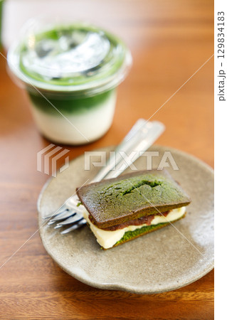 Cup of fresh matcha tea, green tea and Cheese and Matcha and red bean paste financier, small French almond cake, on wooden table. Cup of fresh matcha tea, green tea and Cheese and Matcha and red bean paste financier, small French almond cake, on wooden table. 129834183
