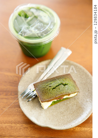 Cup of fresh matcha tea, green tea and Cheese and Matcha and red bean paste financier, small French almond cake, on wooden table. Cup of fresh matcha tea, green tea and Cheese and Matcha and red bean paste financier, small French almond cake, on wooden table. 129834184