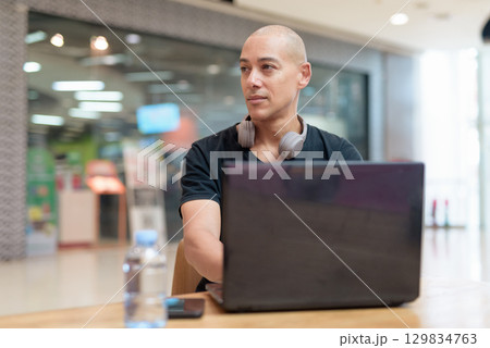 Man working on laptop in mall food court, solo digital productivity concept Man working on laptop in mall food court, solo digital productivity concept 129834763