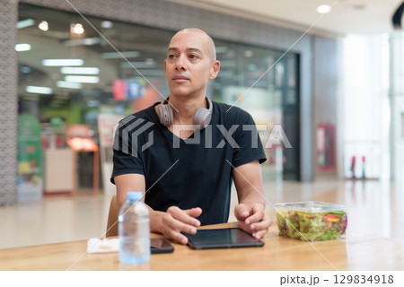 Man eating healthy salad in food court, health and wellness lifestyle 129834918