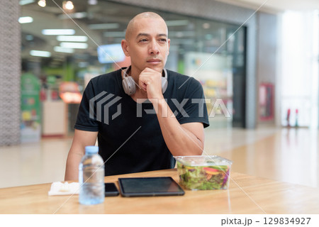Man eating healthy salad in food court, health and wellness lifestyle 129834927