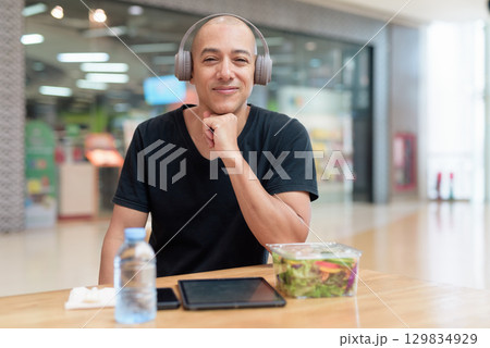 Man eating healthy salad in food court, health and wellness lifestyle Man eating healthy salad in food court, health and wellness lifestyle 129834929
