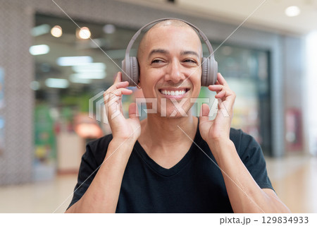 Man listening to music with headphones, relaxing and focused moment Man listening to music with headphones, relaxing and focused moment 129834933