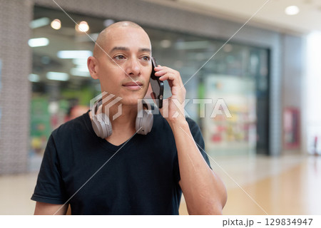 Man talking on mobile phone alone in mall food court, digital lifestyle concept 129834947